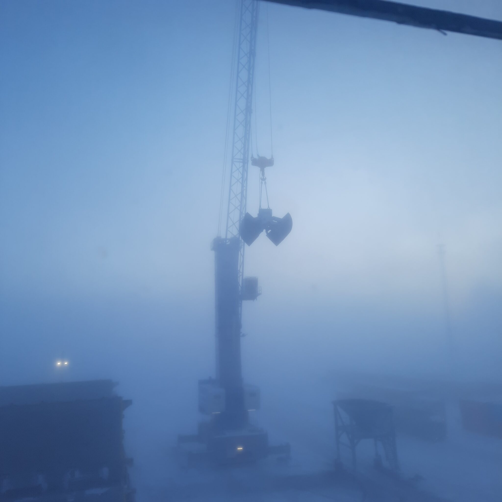 view of cargo ship loading with fog around the crane
